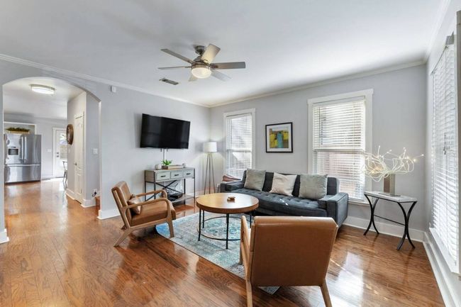 Living area with arched walkways, ceiling fan, wood finished floors, and crown molding | Image 5