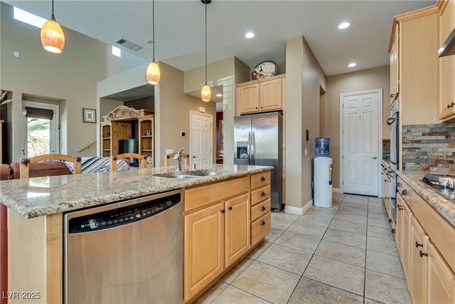 Kitchen with a sink, a center island with sink, stainless steel appliances, light brown cabinets, and visible vents | Image 25