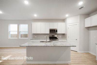 Kitchen with stainless steel appliances, light stone counters, tasteful backsplash, and white cabinetry | Image 3