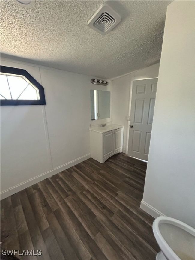 Bathroom with vanity, a textured ceiling, baseboards, wood finished floors, and visible vents | Image 7