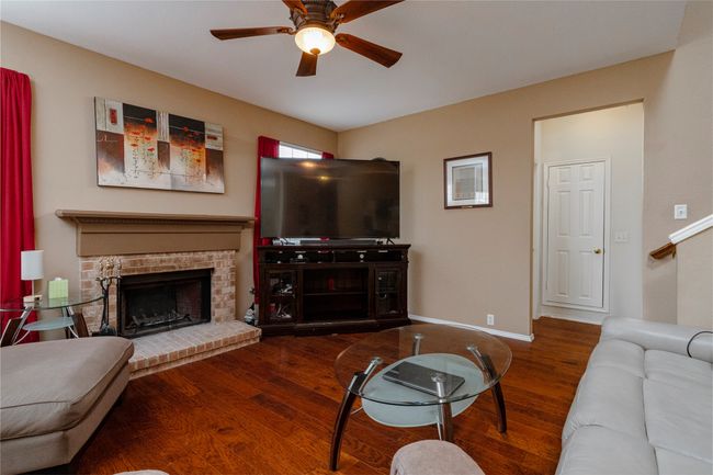Living area with baseboards, a fireplace, wood finished floors, and a ceiling fan | Image 9