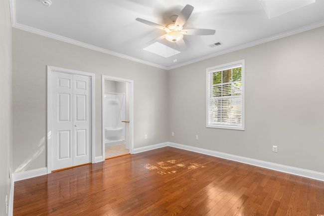 Unfurnished bedroom with wood-type flooring, ornamental molding, baseboards, ceiling fan, and ensuite bath | Image 14