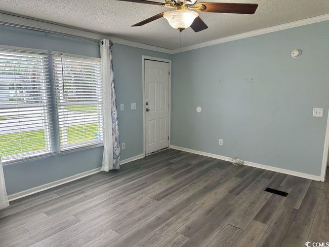 ceiling fan, dark wood finished floors, a textured ceiling, ornamental molding, and baseboards | Image 11