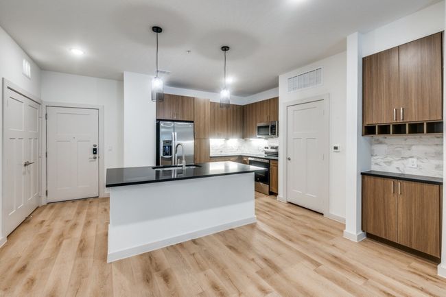 Kitchen featuring brown cabinets, dark countertops, appliances with stainless steel finishes, and light wood finished floors | Image 23