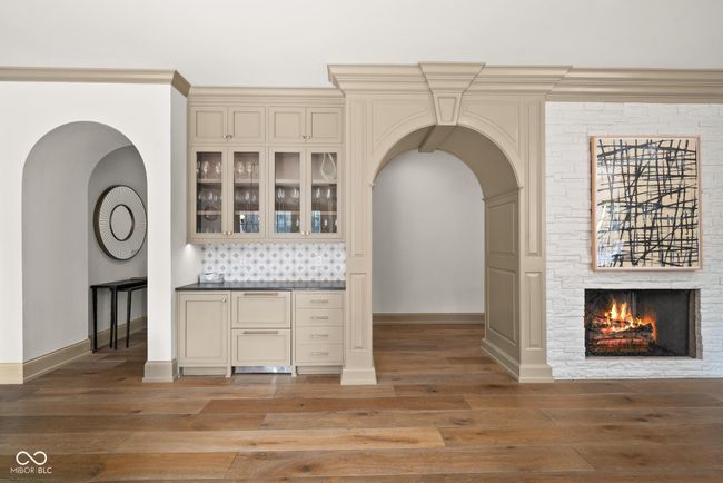 kitchen with cream cabinetry, arched walkways and a fireplace | Image 14
