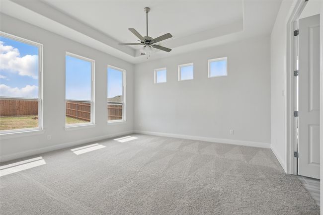 Spare room featuring baseboards, carpet floors, a tray ceiling, and ceiling fan | Image 14