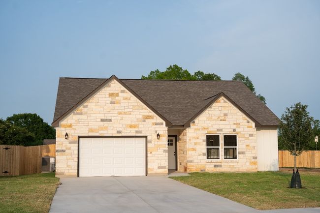 French country style house with a shingled roof, concrete driveway, a garage, and stone siding | Image 5