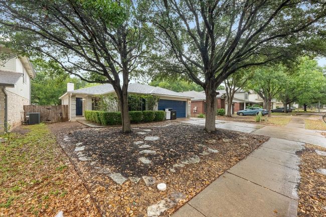 View of front of home with driveway, an attached garage, and brick siding, mature trees. | Image 27