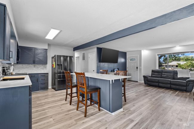 Kitchen with stainless steel fridge, a kitchen breakfast bar, open floor plan, light wood-style flooring, and backsplash | Image 11