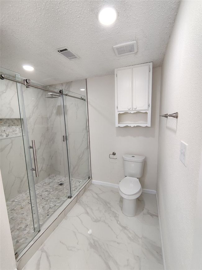 Bathroom featuring tile patterned floors, an enclosed shower, a textured ceiling, and toilet | Image 14