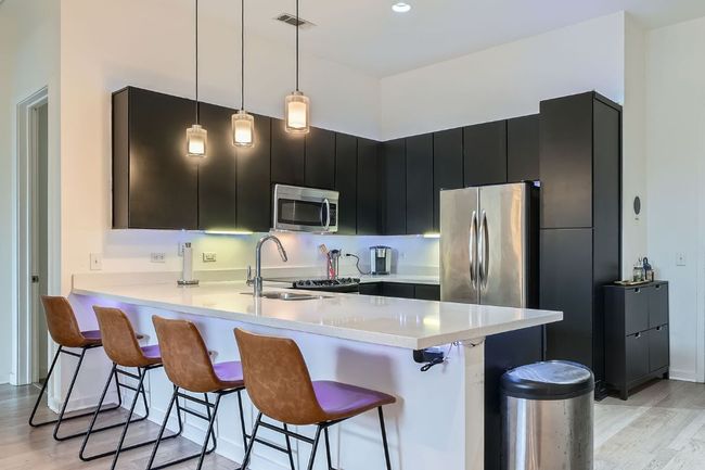 Kitchen featuring a peninsula, stainless steel appliances, a kitchen breakfast bar, and dark cabinetry | Image 11