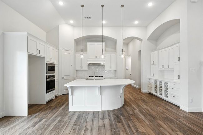 Kitchen featuring dark wood-style tile floors, light countertops, white cabinetry, recessed lighting, and high vaulted ceiling | Image 8