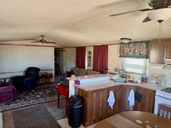 Kitchen featuring ceiling fan, wallpapered walls, lofted ceiling, a sink, and white gas range oven | Image 17