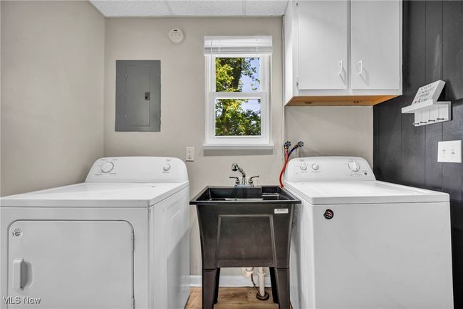 Washroom with electric panel, cabinet space, washer and dryer, and wood finished floors | Image 38