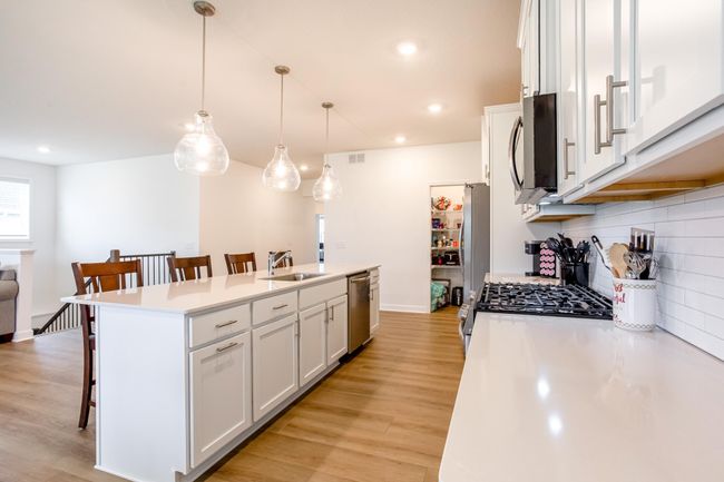 Generous island storage, under-cabinet lighting, and a clean, timeless white-on-white palette complete this well-designed kitchen. | Image 11