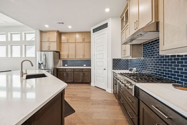 Kitchen with a sink, appliances with stainless steel finishes, light wood-type flooring, glass insert cabinets, and tasteful backsplash | Image 22