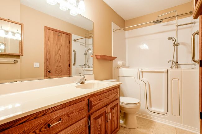 Updated walk-thru main floor bathroom with large vanity, bright lighting, and a walk-in tub for added safety and ease. | Image 19