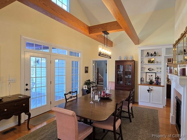 Dining area featuring wood finished floors, stairway, a brick fireplace, beam ceiling, and high vaulted ceiling | Image 17