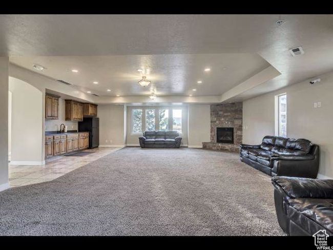 Living room with light colored carpet, baseboards, a stone fireplace, a raised ceiling, and recessed lighting | Image 14
