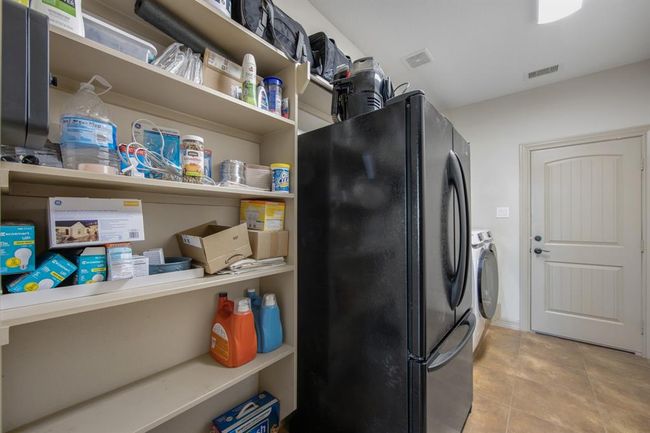 Laundry room with second refrigerator that will stay with property, storage shelves, and tile flooring | Image 31