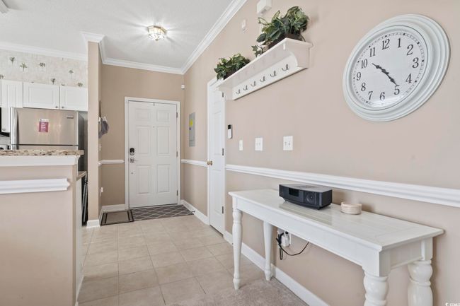 Entrance foyer featuring crown molding, baseboards, and light tile patterned flooring | Image 8