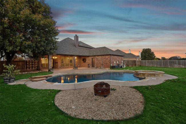Pool at dusk with a lawn, an outdoor fire pit, a patio, and central AC | Image 4