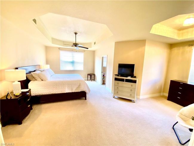 Bedroom with a raised ceiling, ceiling fan, visible vents, and light carpet | Image 10