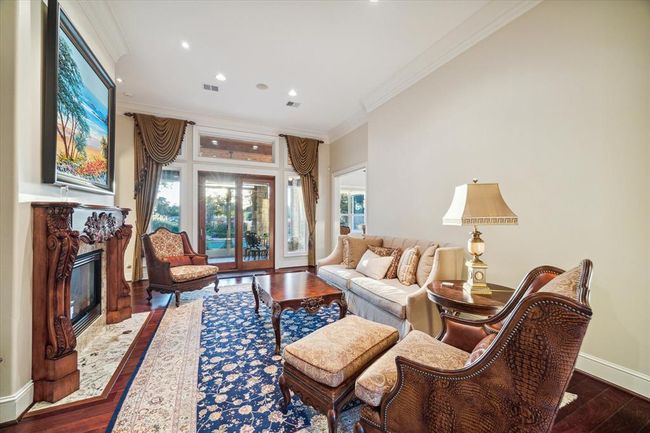 Elegant living room with high ceilings, featuring a classic fireplace, large windows with decorative drapes. The space is bright and inviting, perfect for relaxation and entertaining. | Image 10