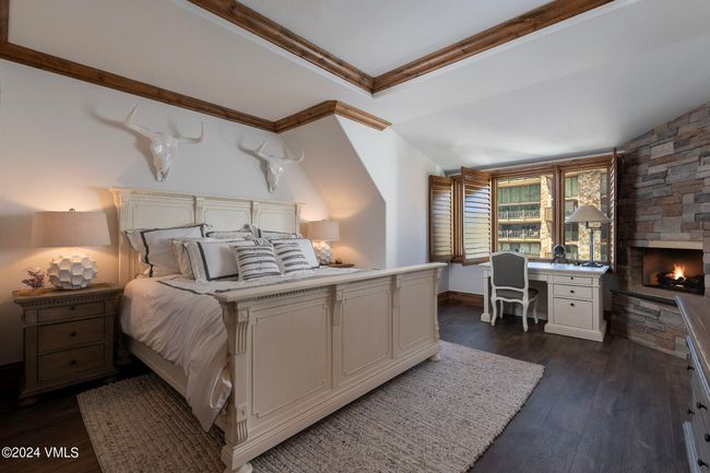 The main-level primary suite is a serene retreat with village views, a private stone fireplace, and cozy textures that invite rest and rejuvenation. | Image 10