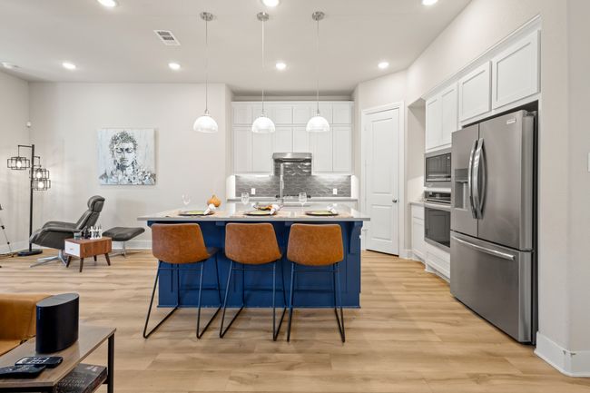 Kitchen featuring visible vents, light wood-style floors, appliances with stainless steel finishes, white cabinetry, and backsplash | Image 9