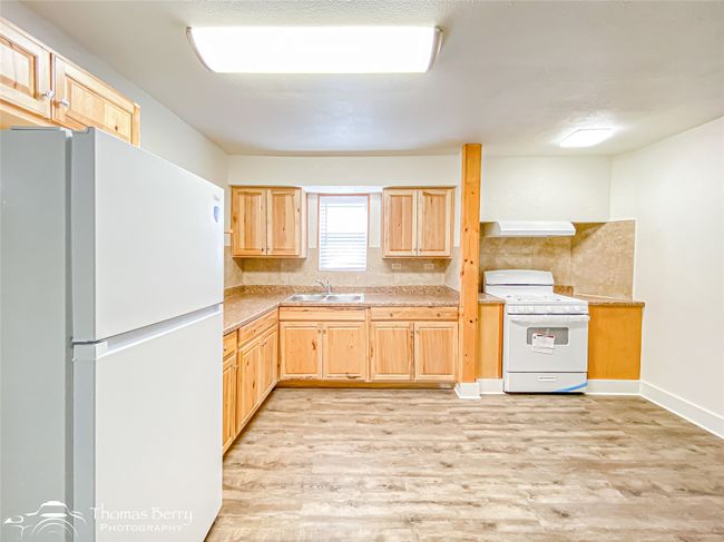 Kitchen with white appliances, light brown cabinetry, light wood finished floors, light countertops, and extractor fan | Image 12