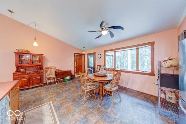 dining room with stone finish flooring, a ceiling fan, and vaulted ceiling | Image 41