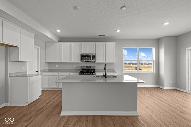 kitchen featuring white cabinetry, a sink, visible vents, light wood-style flooring, and appliances with stainless steel finishes | Image 4