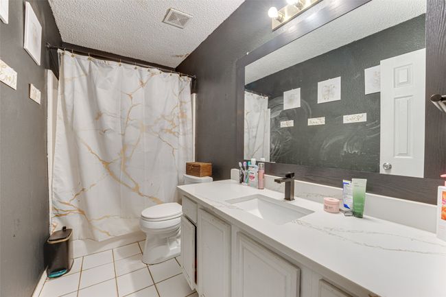Full bath with a textured ceiling, toilet, visible vents, tile patterned flooring, and vanity | Image 7