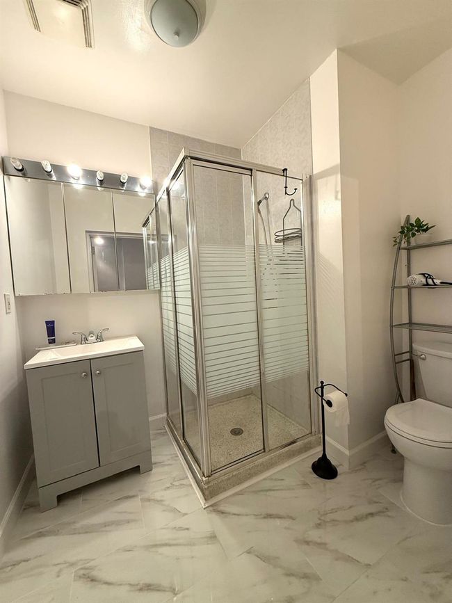Full bathroom featuring toilet, a shower stall, and baseboards | Image 5
