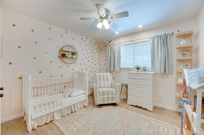 Bedroom with light wood-style floors, a crib, and ceiling fan | Image 22