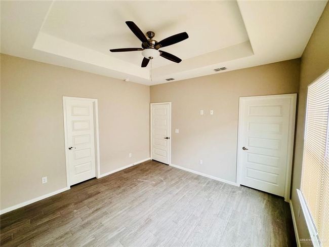 Unfurnished bedroom featuring a raised ceiling, wood finished floors, and ceiling fan | Image 21