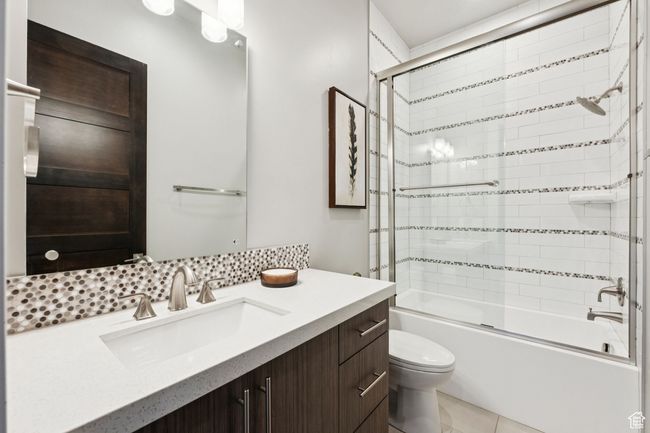 Full bath with vanity, shower / bath combination with glass door, backsplash, and tile patterned flooring | Image 22