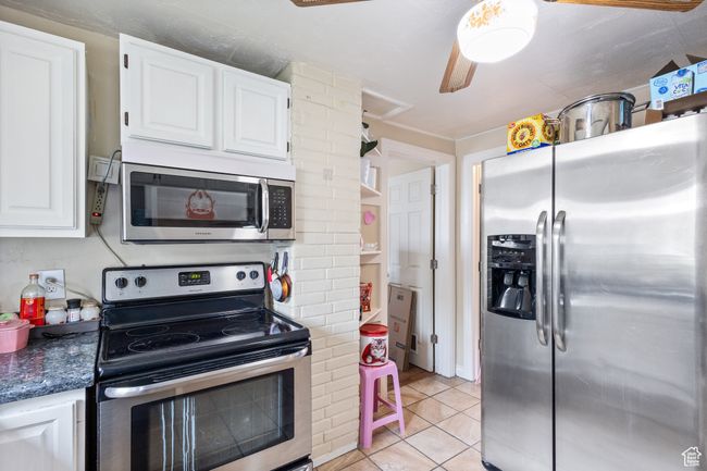 Kitchen with white cabinets, stainless steel appliances, decorative columns, and light tile patterned floors | Image 9