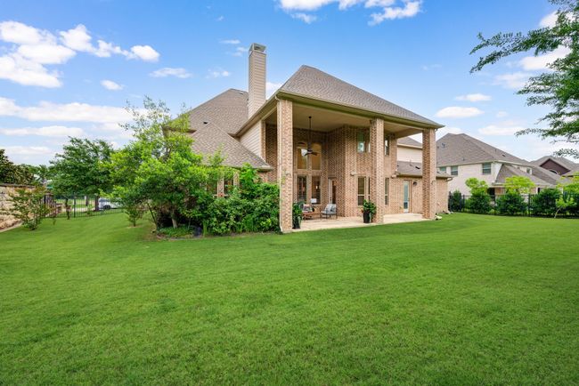 Rear view of property featuring a patio, a chimney, ceiling fan, brick siding, and a shingled roof | Image 33