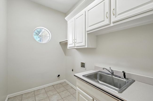 Laundry room featuring washer hookup, cabinet space, electric dryer hookup, and light tile patterned floors | Image 24
