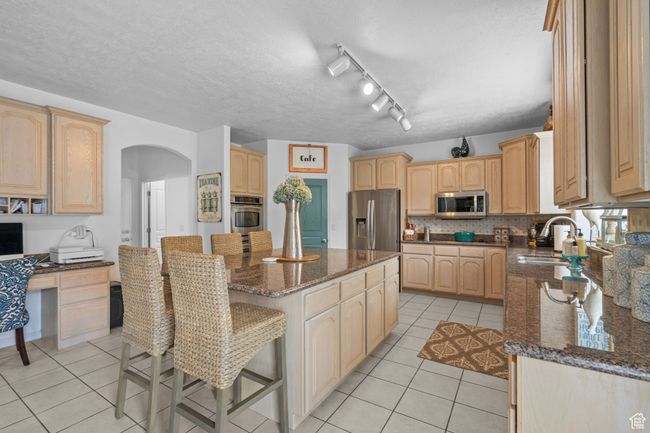 Kitchen featuring a sink, arched walkways, a center island, stainless steel appliances, and light tile patterned floors | Image 15