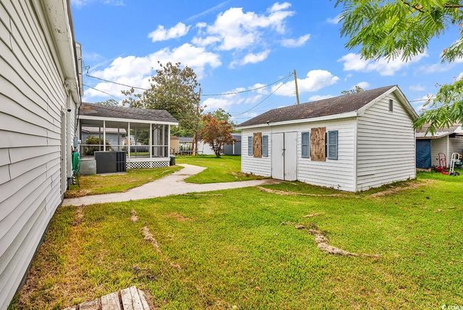 View of green lawn with a sunroom and an outdoor structure | Image 31