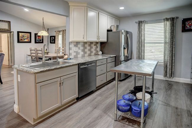 Kitchen with stainless steel appliances, tasteful backsplash, light vinyl finished floors, lofted ceiling, and recessed lighting | Image 14