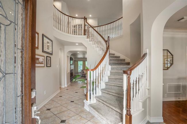 A light reflecting glass lead and wood surrounding door leads into your new home with spiral staircase leading upstairs. | Image 6