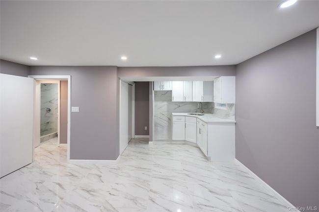 Kitchen featuring white cabinetry, light marble finish flooring, recessed lighting, decorative backsplash, and light stone countertops | Image 27