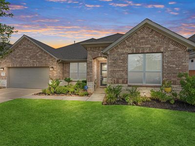 Charming single-story brick home with a well-manicured lawn, two-car garage, and inviting entryway, captured at dusk with a beautiful sunset sky. | Image 1