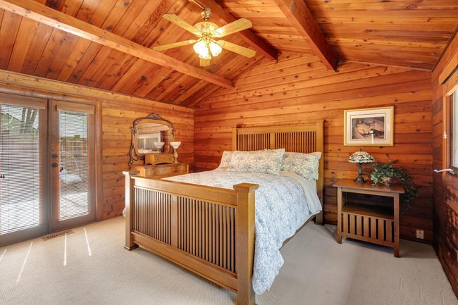 Carpeted bedroom featuring access to exterior, wooden walls, french doors, wood ceiling, and ceiling fan | Image 19