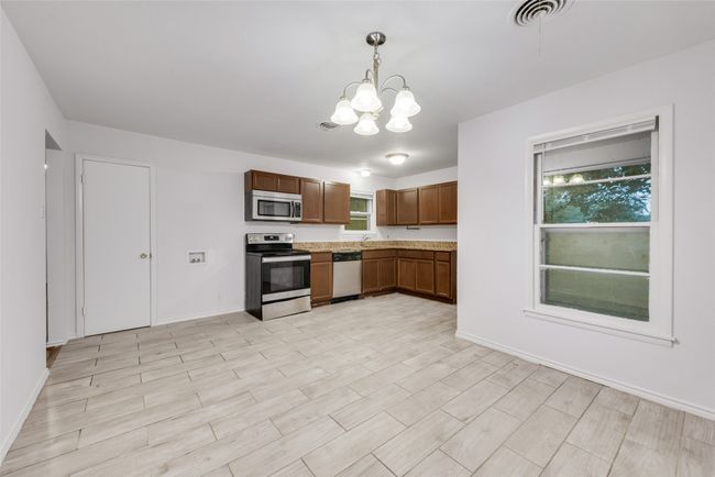 Kitchen with a chandelier, light countertops, decorative light fixtures, appliances with stainless steel finishes, and visible vents | Image 6