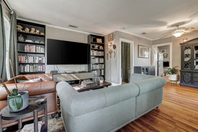 Living room featuring a ceiling fan, ornamental molding, wood finished floors, and visible vents | Image 6